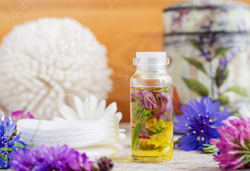 Small bottle with wild flowers infusion (extract, tincture, essential oil). Aromatherapy, spa and herbal medicine concept. Copy space.