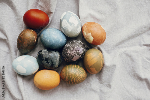 Stylish easter eggs on rustic table, flat lay. Natural dyed colorful easter eggs on rural linen textile background. Space for text.