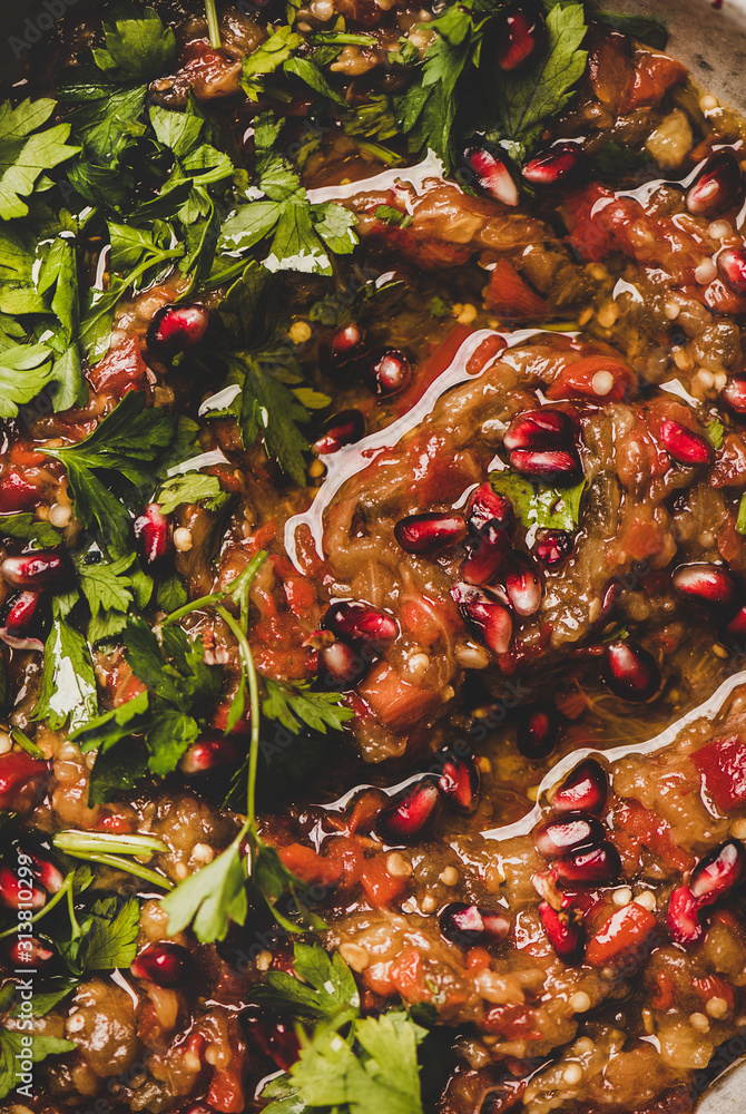 Turkish, Middle East traditional meze starter. Flat-lay of Babaganoush dip seasoned with parsley, lemon and pomegranate seeds, close-up. Oriental typical salad