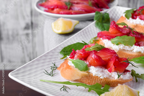 Trout Gravlax on the slices of white bread with ricotta topped with greenery against the white background. Nordic cuisine meal