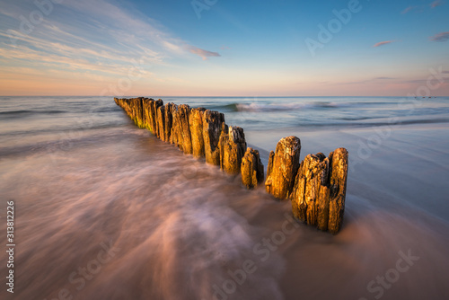 Fototapeta Naklejka Na Ścianę i Meble -  Baltic Sea. Wooden piles on the beach during sunset.