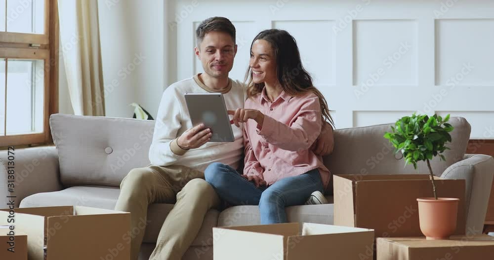 Happy couple using tablet talking on sofa on moving day Happy couple using tablet talking on sofa on moving day
