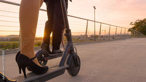 LOW ANGLE: Two co-workers ride modern electric scooters to work at sunrise.