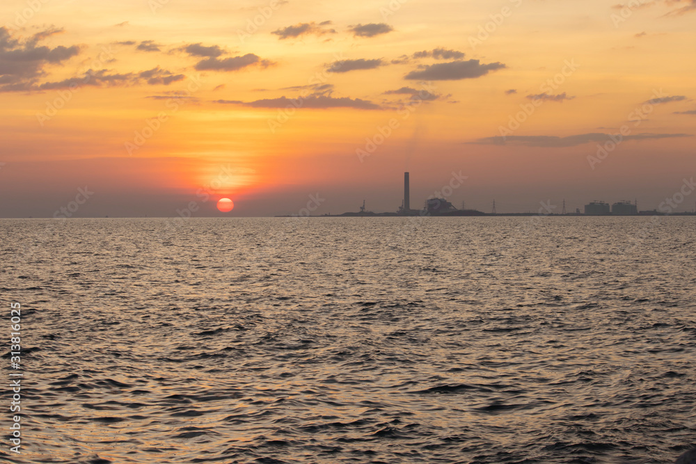 The red sun over the evening sea near the industrial area by the sea