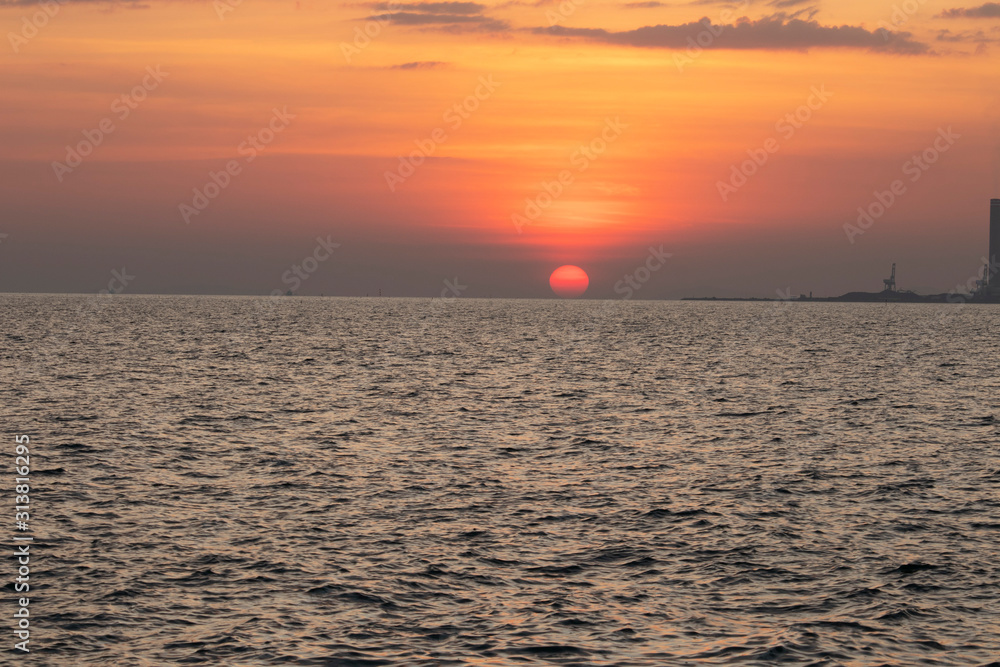 The red sun over the evening sea near the industrial area by the sea