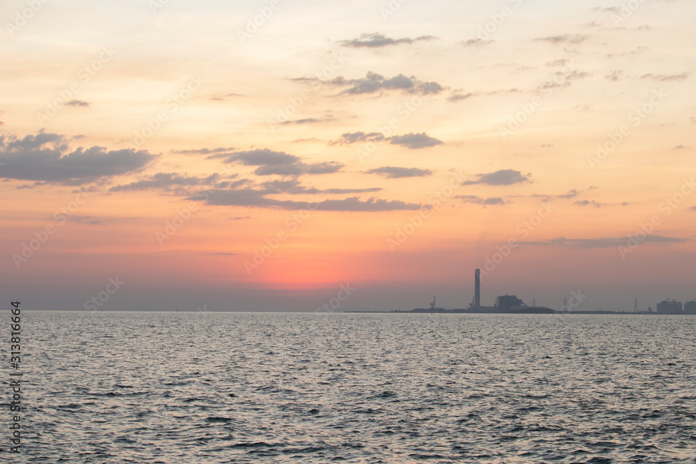 The red sun over the evening sea near the industrial area by the sea The red sun over the evening sea near the industrial area by the sea