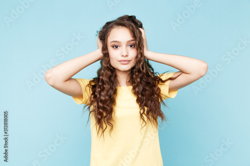 Pretty young woman holding her hair standing in the blue studio
