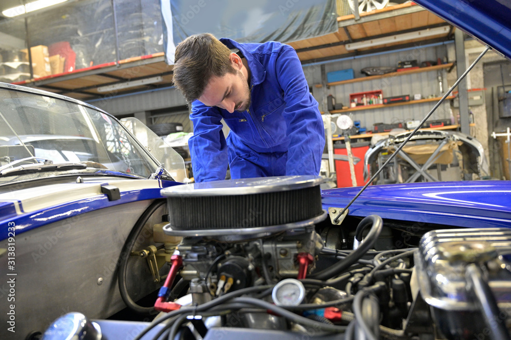 Apprentice working on car engine in workshop Apprentice working on car engine in workshop