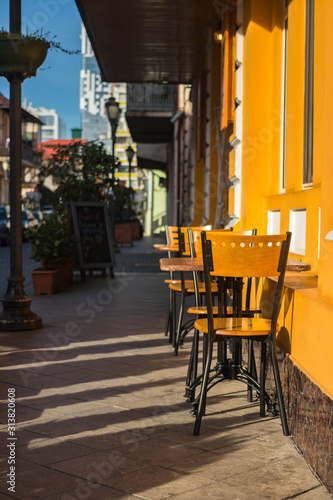 Empty chairs of summer cafe standing outside on the street in historical part of touristic European city old center  Morning light.
