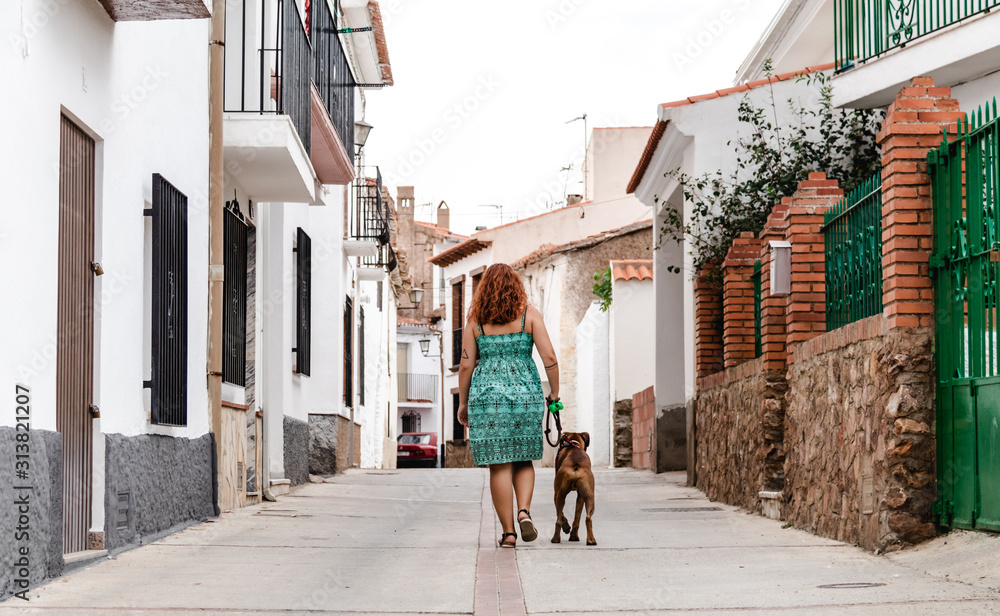 young woman walking down the street with boxer dog