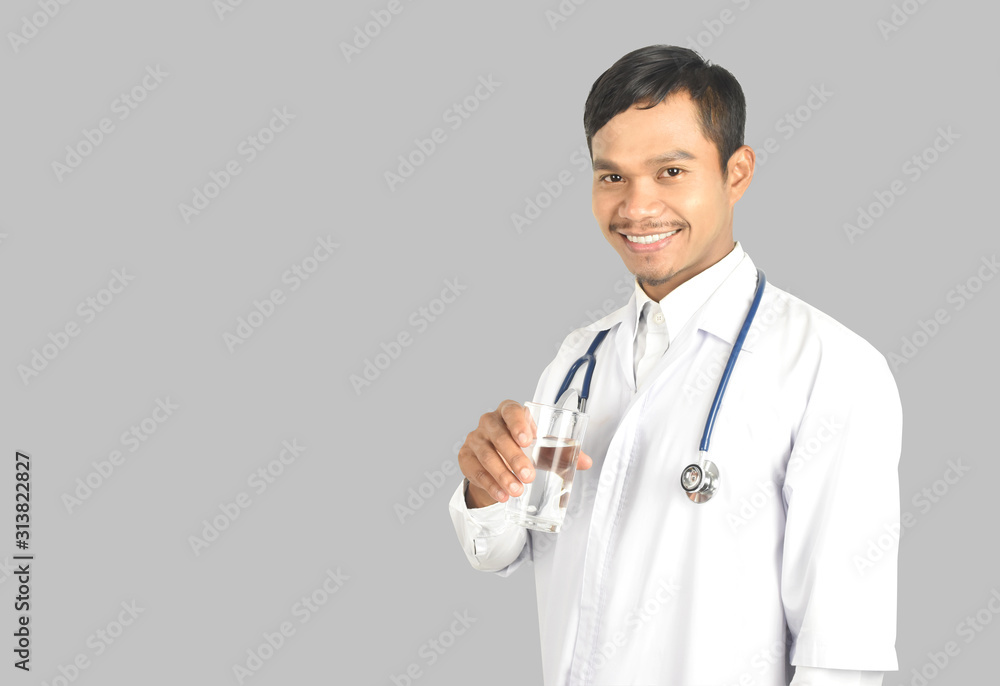 young man doctor with stethoscope standing and holding glass of water on white background. young man doctor with stethoscope standing and holding glass of water on white background.