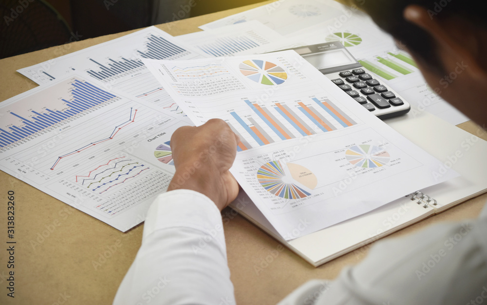 Obraz premium businessman analyzing financial graphs and charts report on desk in office.