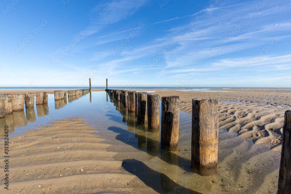 Beach with pure sand, footprints and breakwater with a blue sky in the morning