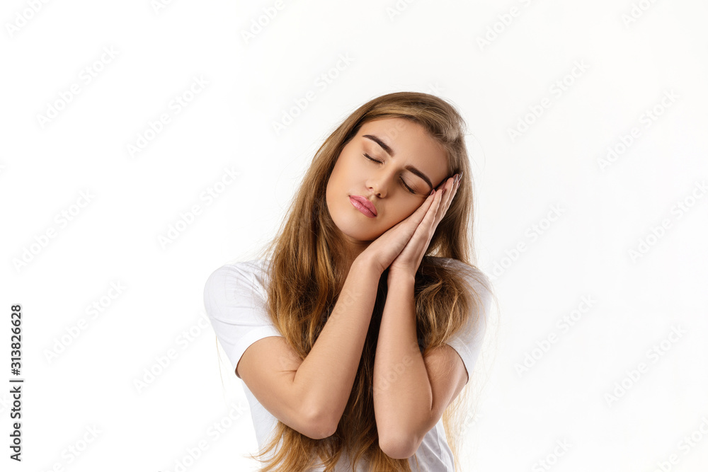 Portrait of young beautiful woman in t-shirt showing sleep gesture on white background Portrait of young beautiful woman in t-shirt showing sleep gesture on white background