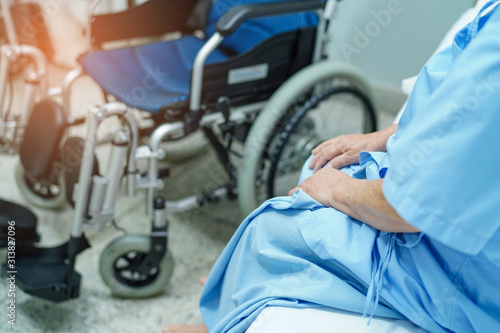 Asian senior or elderly old lady woman patient sitting on bed with electric wheelchair at nursing hospital ward : healthy strong medical concept .