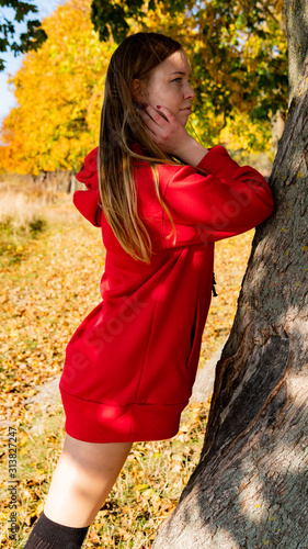 Incredible stunning girl in a red dress. The background is fantastic autumn. Artistic photography.
