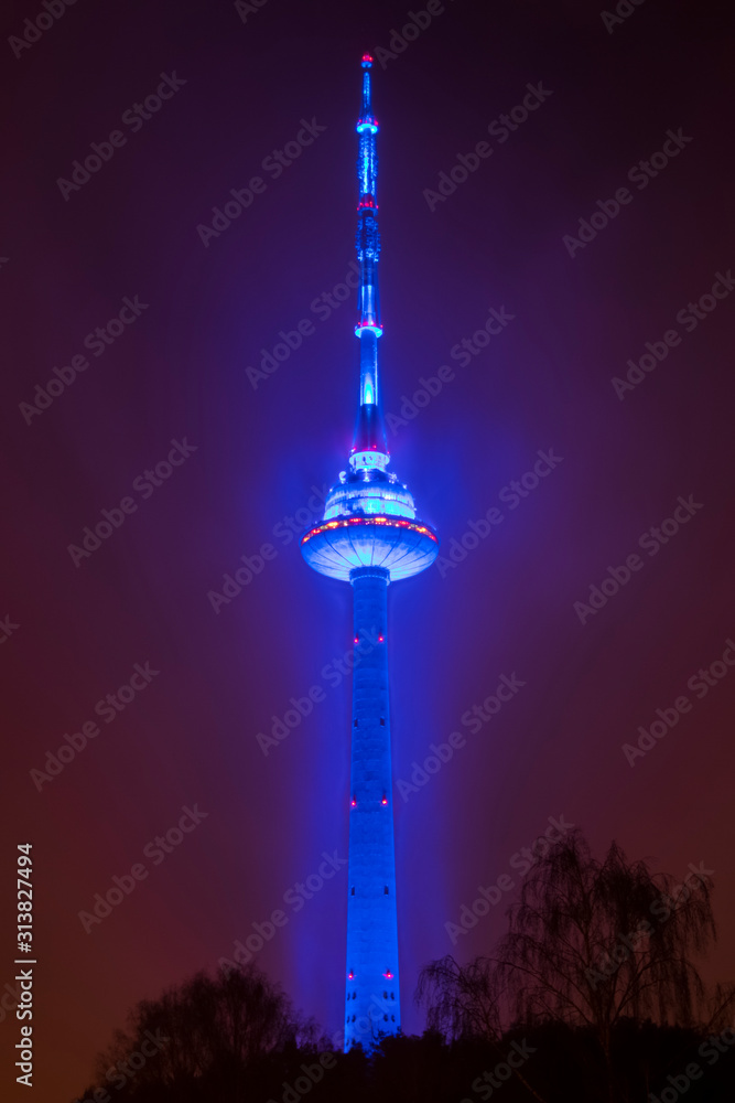 blue illuminated TV tower in lite haze