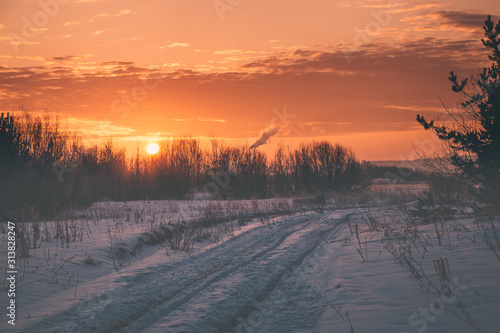 a road through a snowy field is beautifully lit by the rising sun