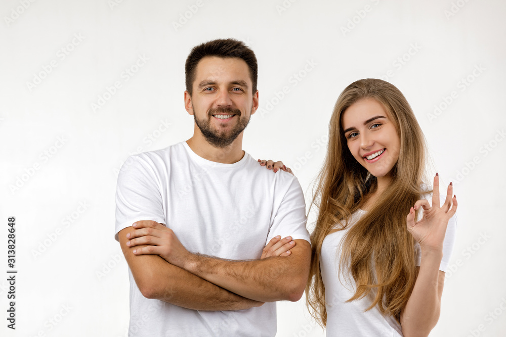 beautiful happy couple looking at camera on white background. woman showing Ok gesture.