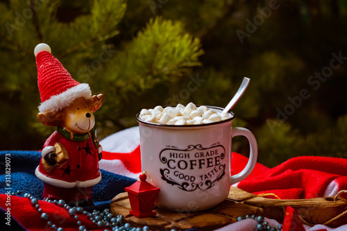 Mug of cocoa with marshmallows on a dark background on a dark background and green spruce