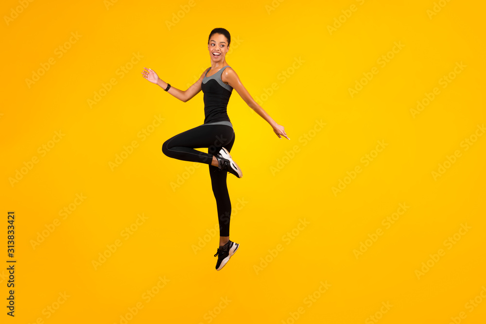 Afro Lady Jumping Exercising In Studio On Yellow Background