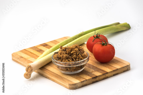 Domestic salty fried Pork greaves, duvan cvarci, in a Glass Bowl with Tomato and Leek on a Cutting Board and on white background Table photo