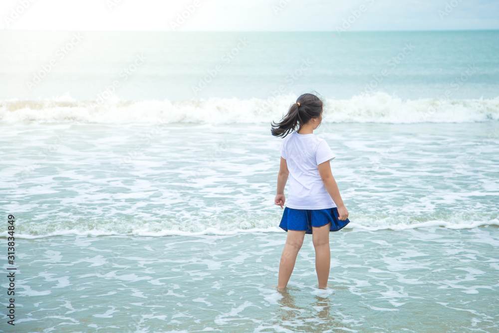 Asian girls Wearing a white shirt, blue pants Stand looking at the white waves in the blue sea Asian girls Wearing a white shirt, blue pants Stand looking at the white waves in the blue sea