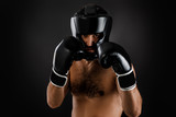 Muscular boxer man with boxing gloves ready to fight on black background. man wearing protective gear