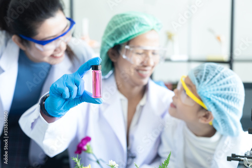 Close up oil and essential with asian girl leaning and education with team science lab research flower with microscope for Natural alternative herb from fresh flower of for new product skin care 