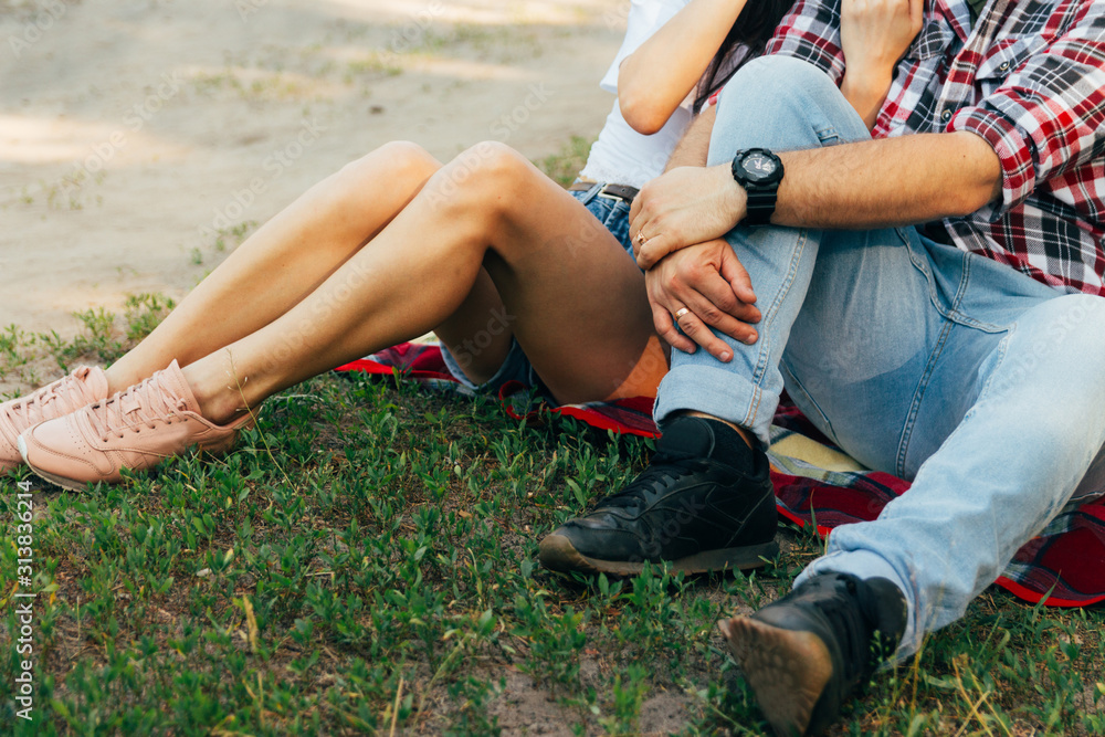 loving couple sits on a red plaid in the woods and embrace.the couple is kissing loving couple sits on a red plaid in the woods and embrace.the couple is kissing