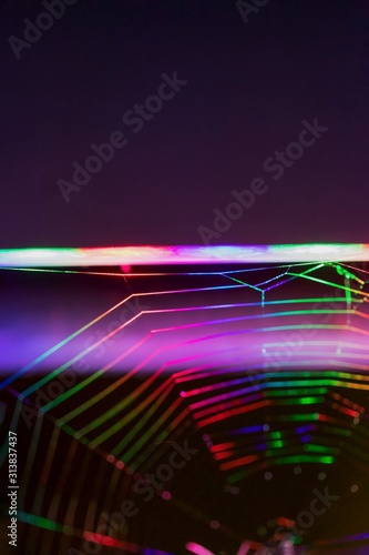 Bright ultra colored spider web or cobweb on a dark background. Technology background concept. Neon illumination. Copy space
