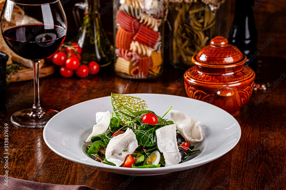 Spanish cuisine. Mixed salad fish salad, spinach, quail eggs, canned mackerel, olives, seasoned