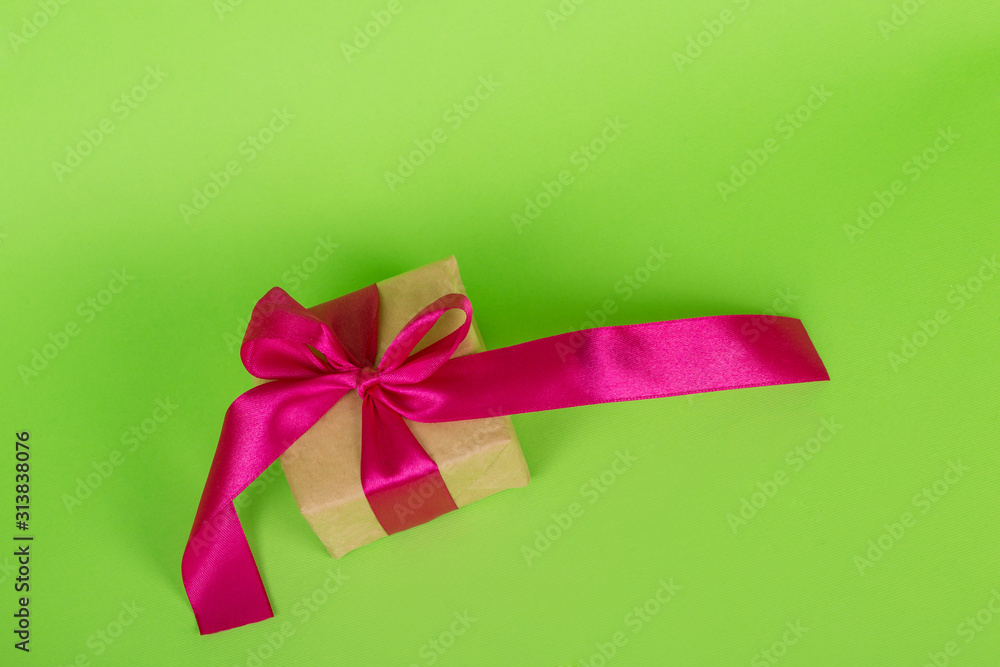 Womans day concept. Gift box wrapped in craft paper. gift with a pink ribbon on a green background. Womans day concept. Gift box wrapped in craft paper. gift with a pink ribbon on a green background.