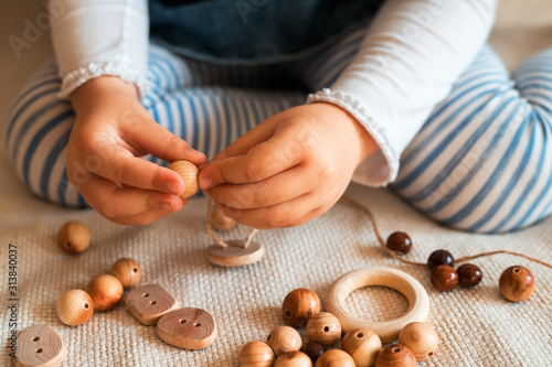 Childs hands threading beads and making bracelet. Close up.