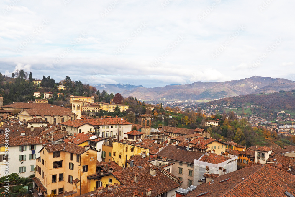 Aerial view of Bergamo old town with mountain range behind.