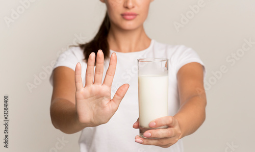 Unrecognizable Lady Holding Milk Gesturing No To Glass, Gray Background photo