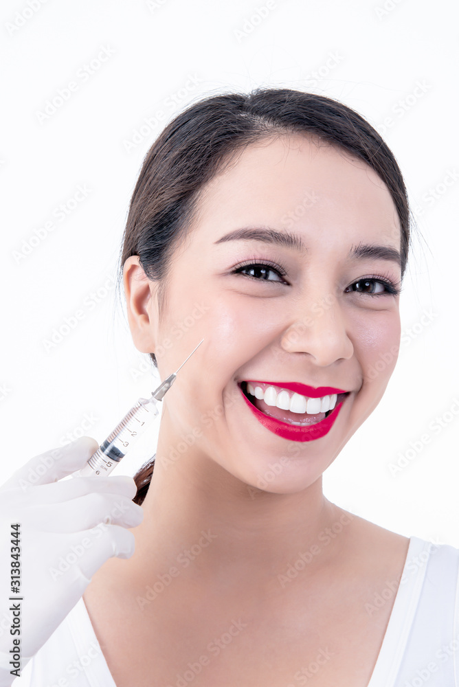 Portrait images of Asian pretty young woman, smiling, beautiful white and clean teeth And syringe placed on the face Ready for injection On white background to Cosmetic surgery concept.