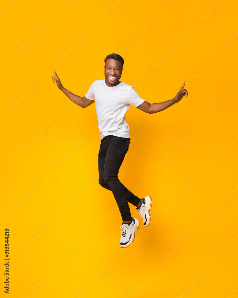 Obraz premium Afro Man Having Fun Jumping In Air Over Yellow Background