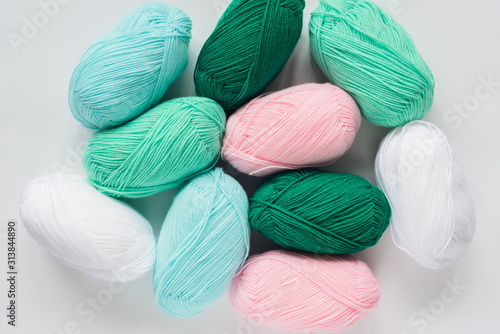 oval acrylic pastel colored wool yarn thread skeins lying on white background, top-down view flat lay still life, horizontal stock photo image