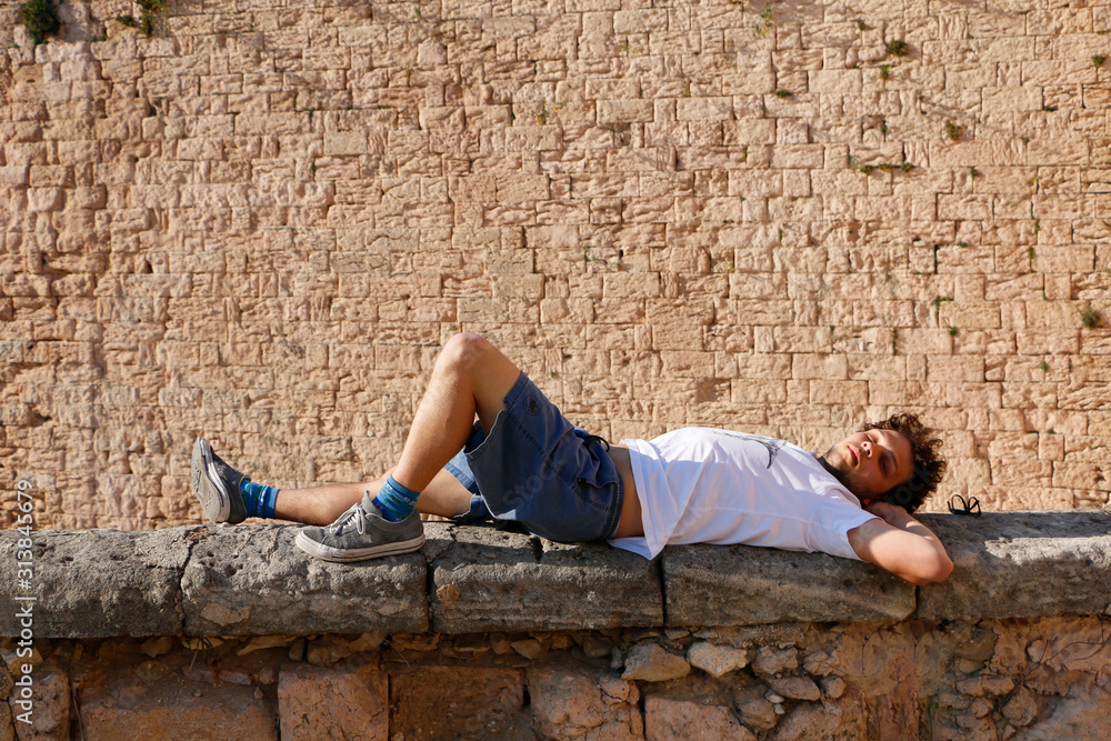 Young man relaxing on a stonewall