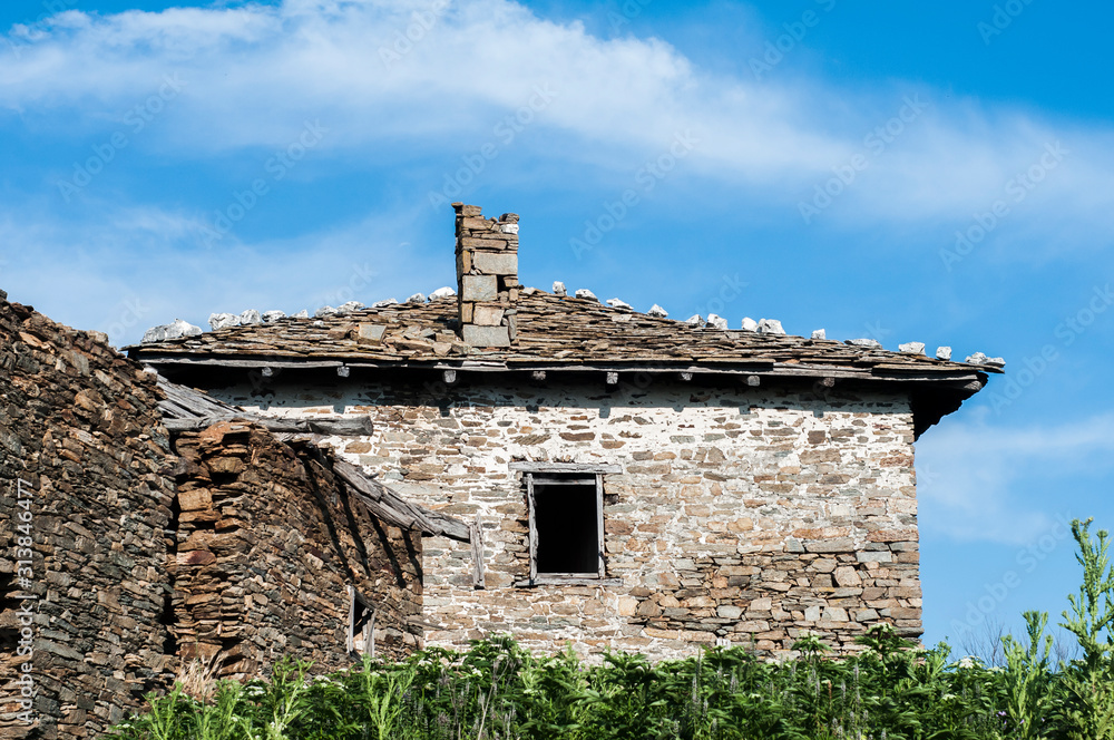 Old rural country stone house facade in sunny summer day