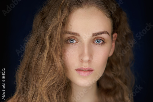 close-up portrait of beautiful woman with long curly blond hair on black background