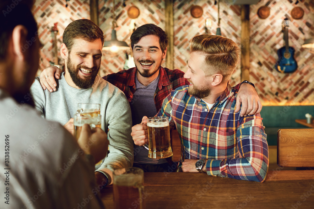 Group friends clinking glasses of beer in a bar.