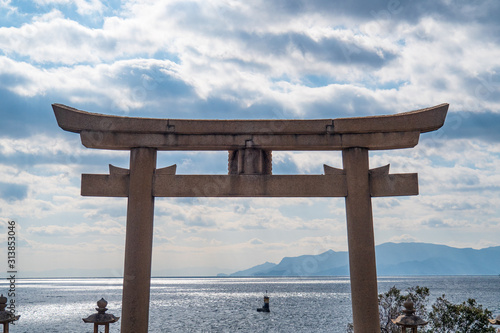 海沿いにある神社の鳥居と、雲の隙間から光が差し込む瀬戸内海。