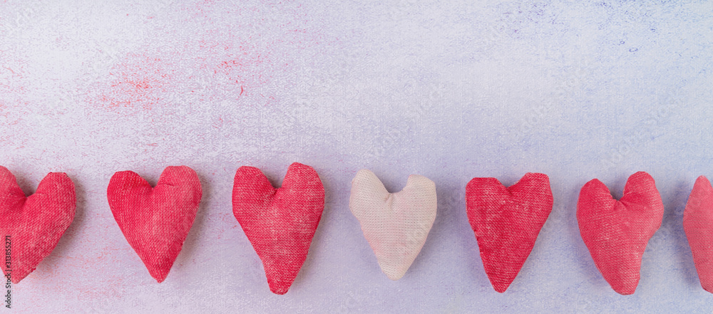 Row of hand made fabric hearts craft top view on pink background Row of hand made fabric hearts craft top view on pink background