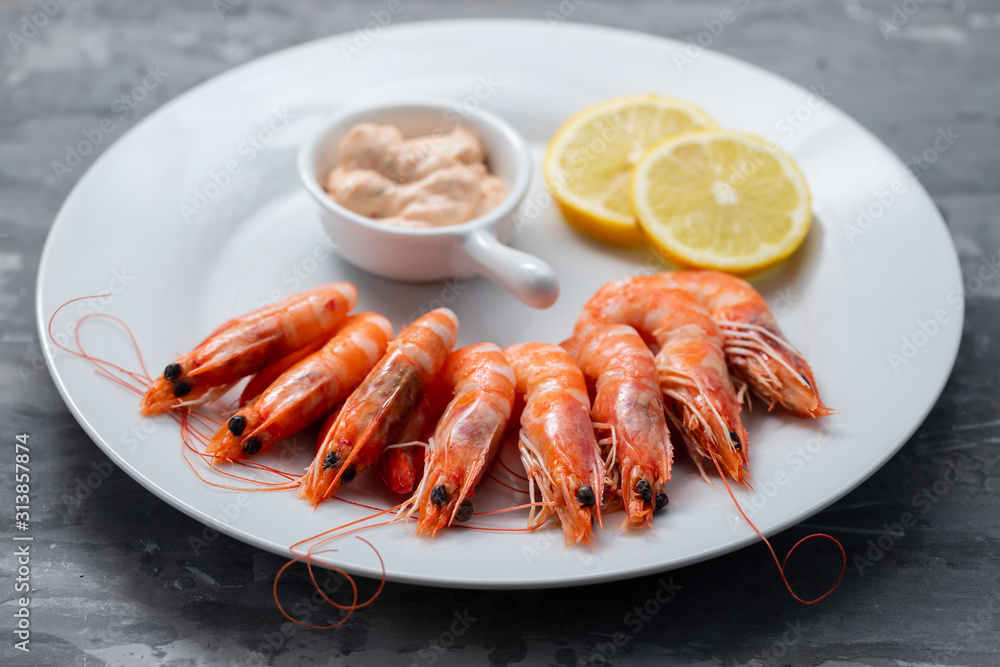 boiled shrimps with lemon and sauce on white dish on ceramic background boiled shrimps with lemon and sauce on white dish on ceramic background