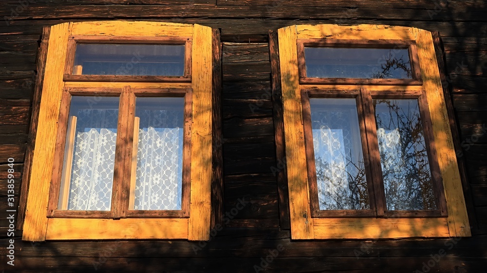 Two yellow coloured wooden antique window frames on historical blockhouse building in northern Slovakia, morning sunshine. Two yellow coloured wooden antique window frames on historical blockhouse building in northern Slovakia, morning sunshine.