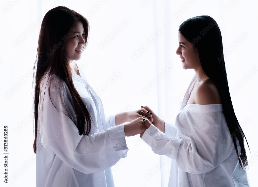 The beautiful women standing beside window,holding hands together,feeling loved,portrait of model posing,blurry light around The beautiful women standing beside window,holding hands together,feeling loved,portrait of model posing,blurry light around