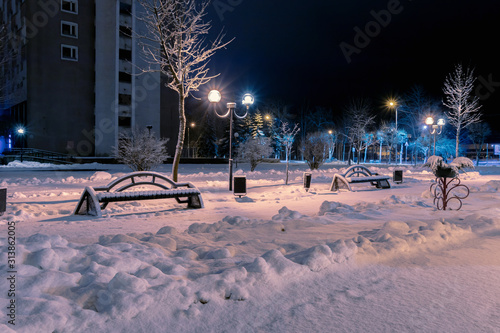 Snow covered benches in a deserted night city park