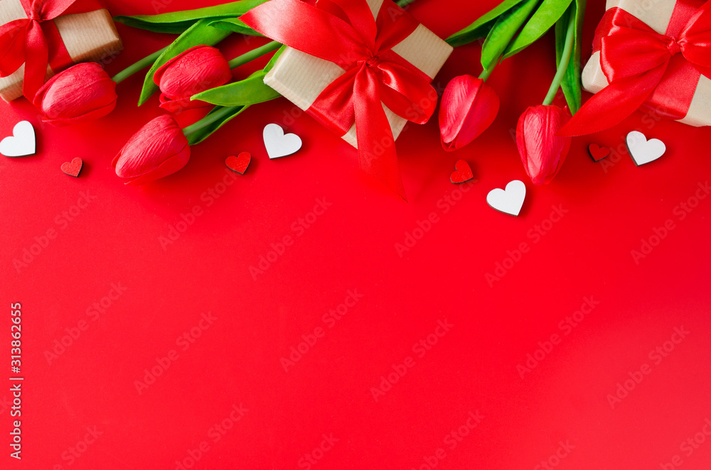 Red tulips, gift boxes and wooden hearts on red background. Greeting card for Valentine's Day. Red tulips, gift boxes and wooden hearts on red background. Greeting card for Valentine's Day.